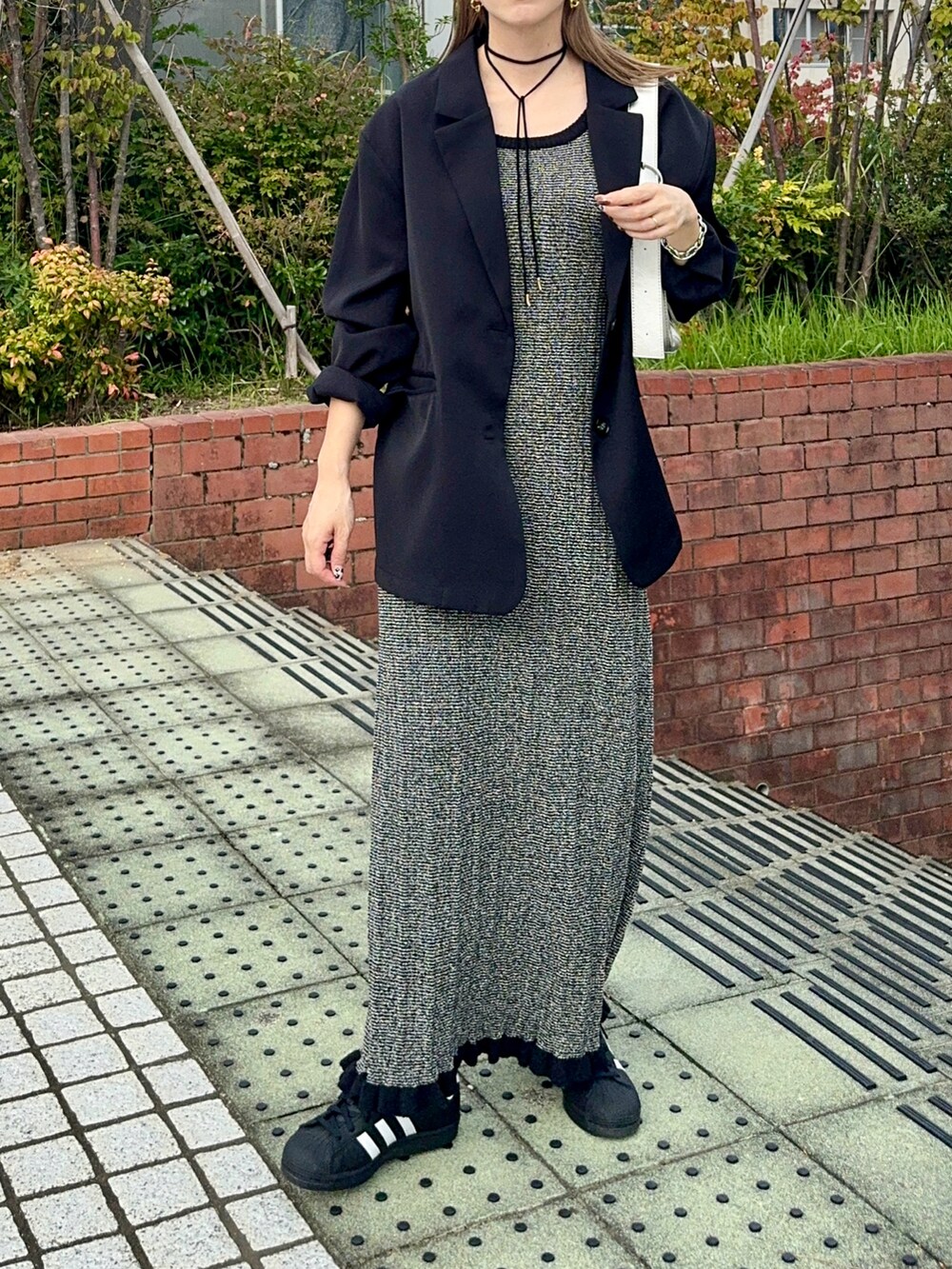 ブラック系のテーラードジャケット、ブラック系のワンピース、ブラック系のスニーカーを着用したレディースの秋コーディネートの4枚目の写真