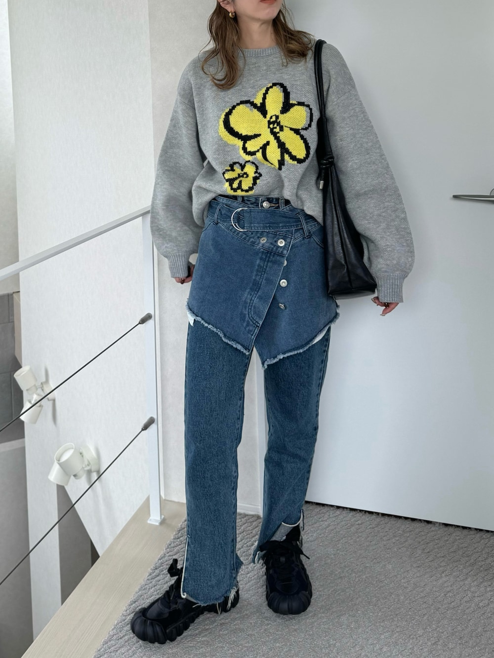 グレー系のニット/セーター、ブラック系のスニーカー、ブラック系のショルダーバッグを着用したレディースの秋コーディネートの3枚目の写真