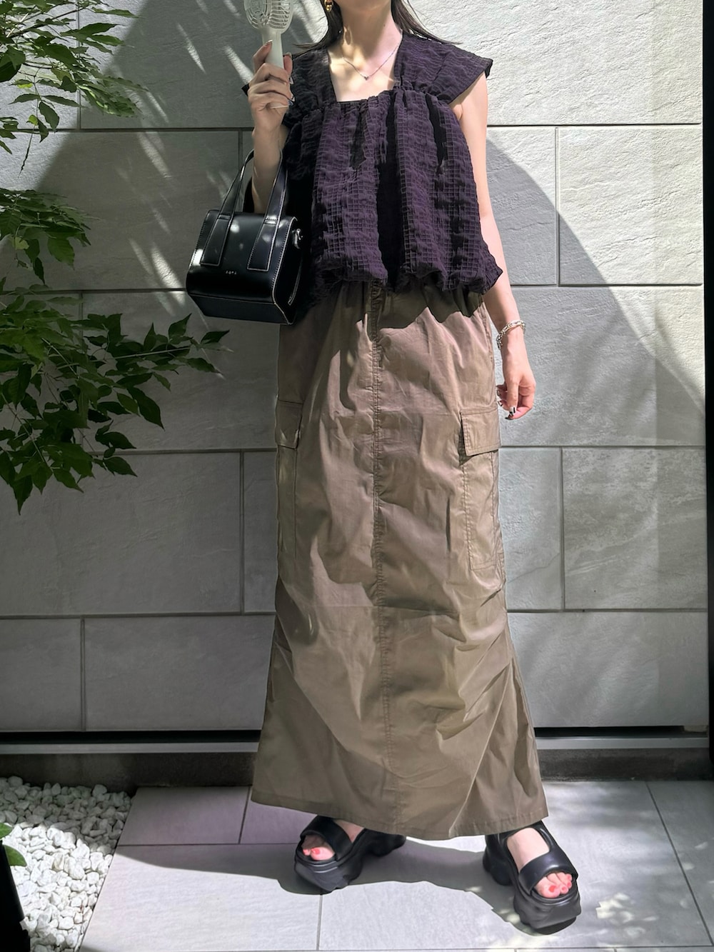 ブラック系のその他トップス、グリーン系のスカート、ブラック系のサンダルを着用したレディースの夏コーディネートの3枚目の写真