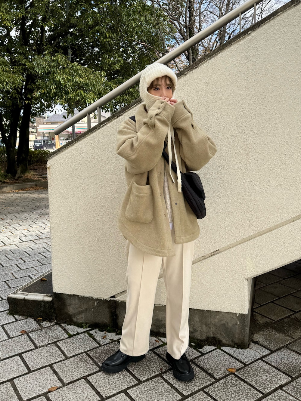 グリーン系のその他アウター、ブラック系のブーツ、ホワイト系のニット/セーターを着用したレディースの冬コーディネートの2枚目の写真