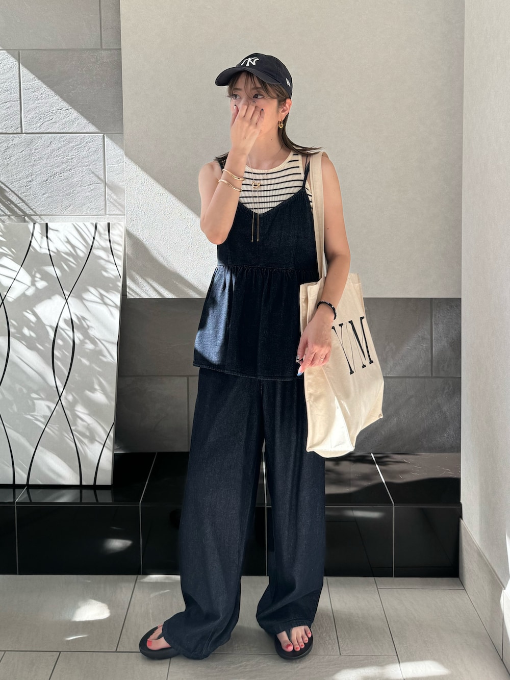 ブルー系のキャミソール、ブルー系のデニムパンツ、ホワイト系のトートバッグを着用したレディースの夏コーディネートの2枚目の写真