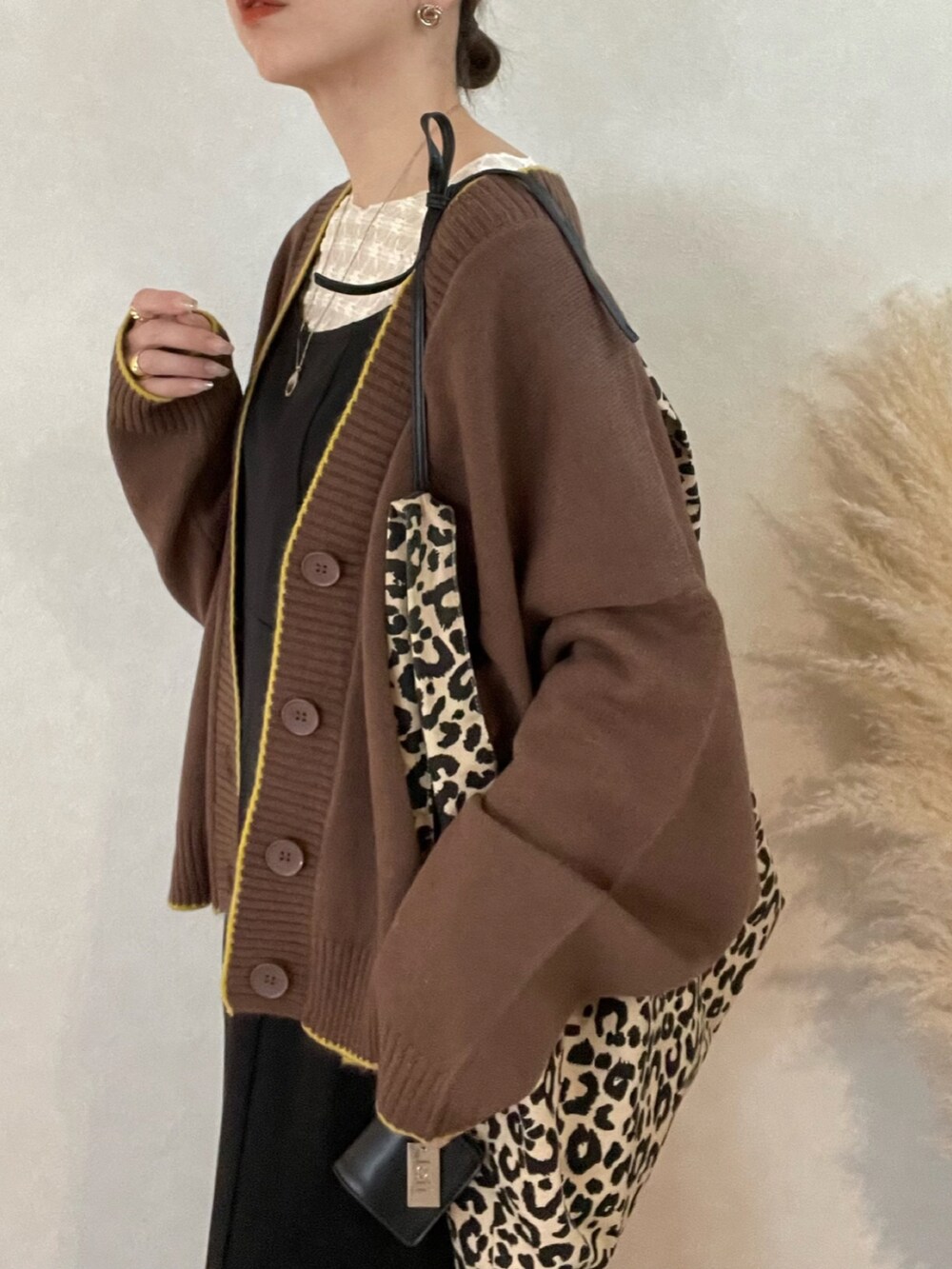 ブラウン系のカーディガン/ボレロ、ブラック系のワンピース、ホワイト系のブーツを着用したレディースの冬コーディネートの4枚目の写真