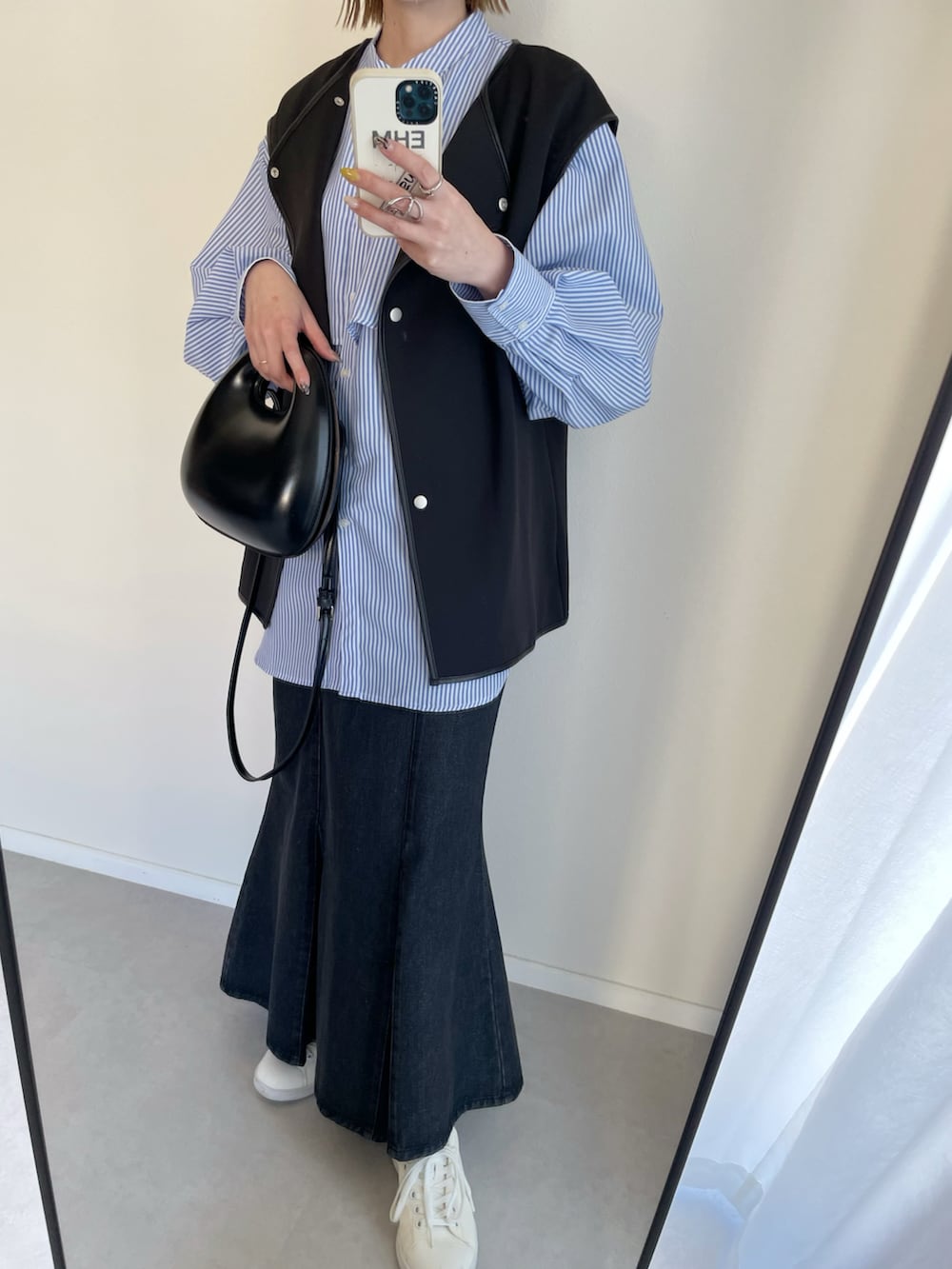 ブルー系のシャツ/ブラウス、ブラック系のベスト、ブラック系のスカートを着用したレディースの春コーディネートの2枚目の写真