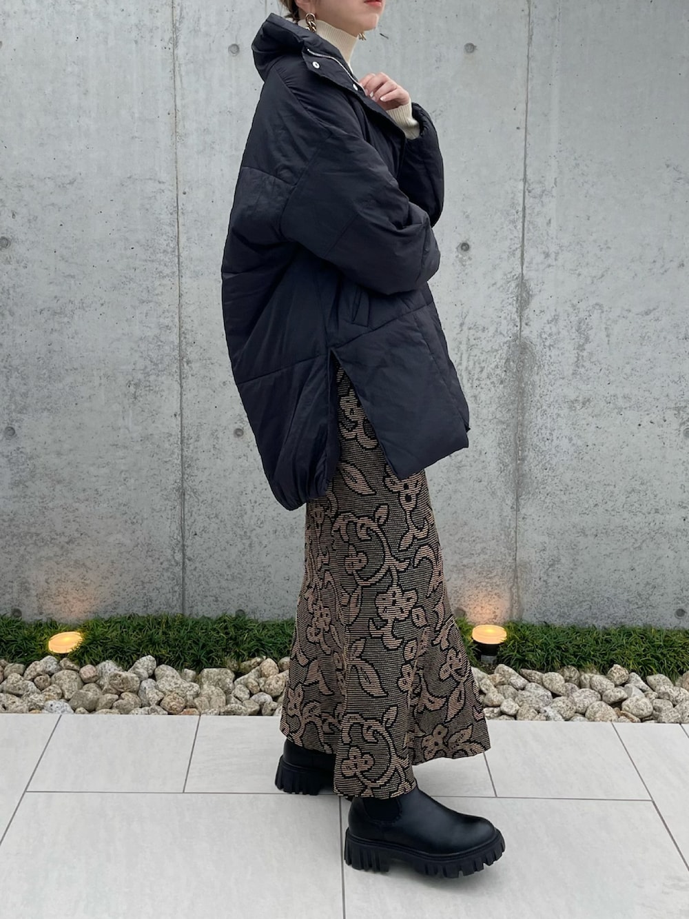 ブラック系のダウンジャケット/コート、ホワイト系のニット/セーター、ブラック系のブーツを着用したレディースの秋コーディネートの3枚目の写真