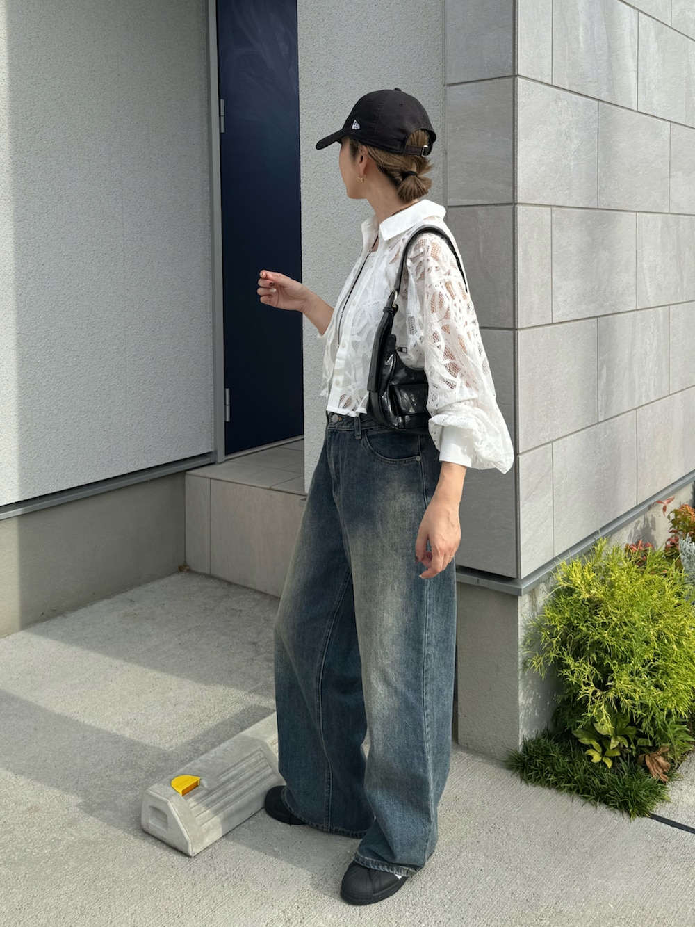 ブルー系のデニムパンツ、ブラック系のショルダーバッグ、ブラック系のスニーカーを着用したレディースの夏コーディネートの2枚目の写真