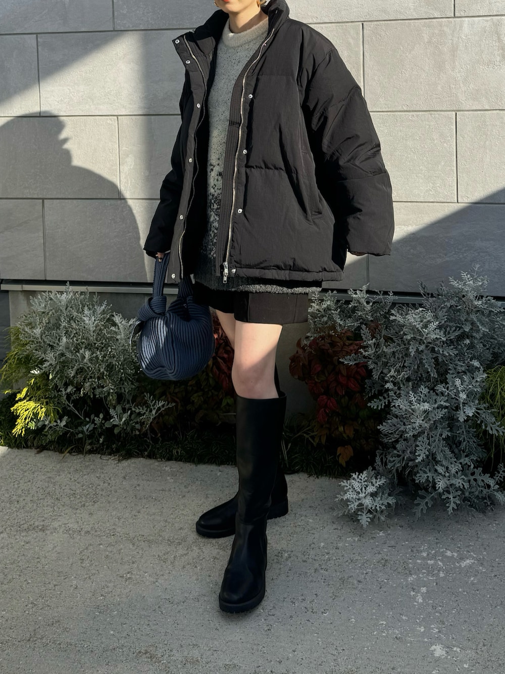 ブラック系のダウンジャケット/コート、ホワイト系のニット/セーター、ブルー系のハンドバッグを着用したレディースの冬コーディネートの2枚目の写真