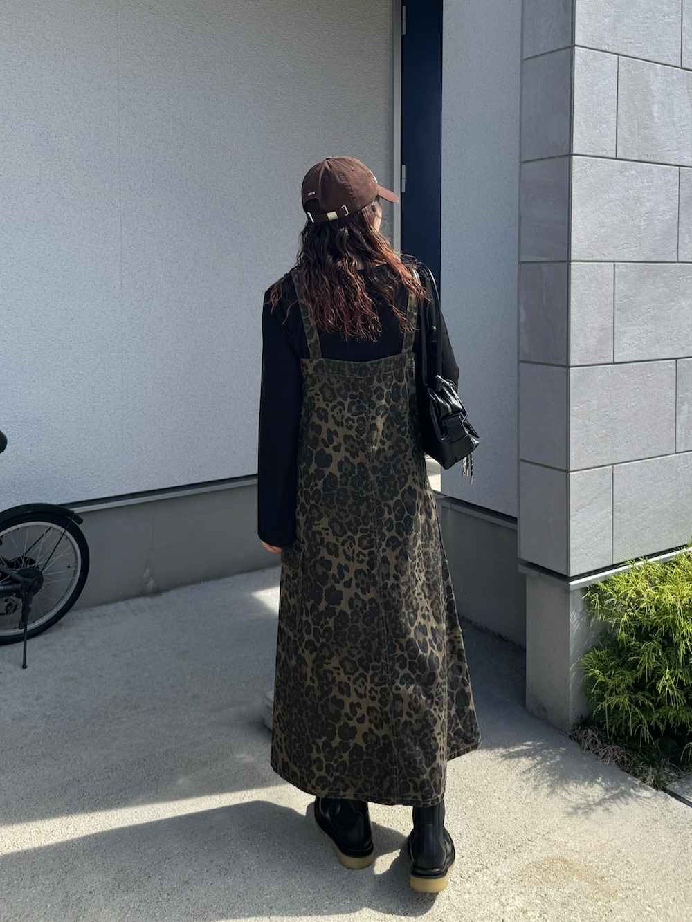 ブラック系のボストンバッグ、ブラック系のブーツ、ブラウン系のキャップを着用したレディースの秋コーディネートの5枚目の写真