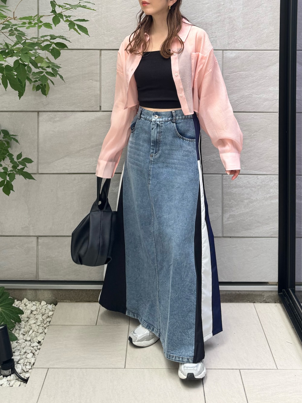 ブラック系のハンドバッグ、ブルー系のスカート、グレー系のスニーカーを着用したレディースの夏コーディネートの3枚目の写真