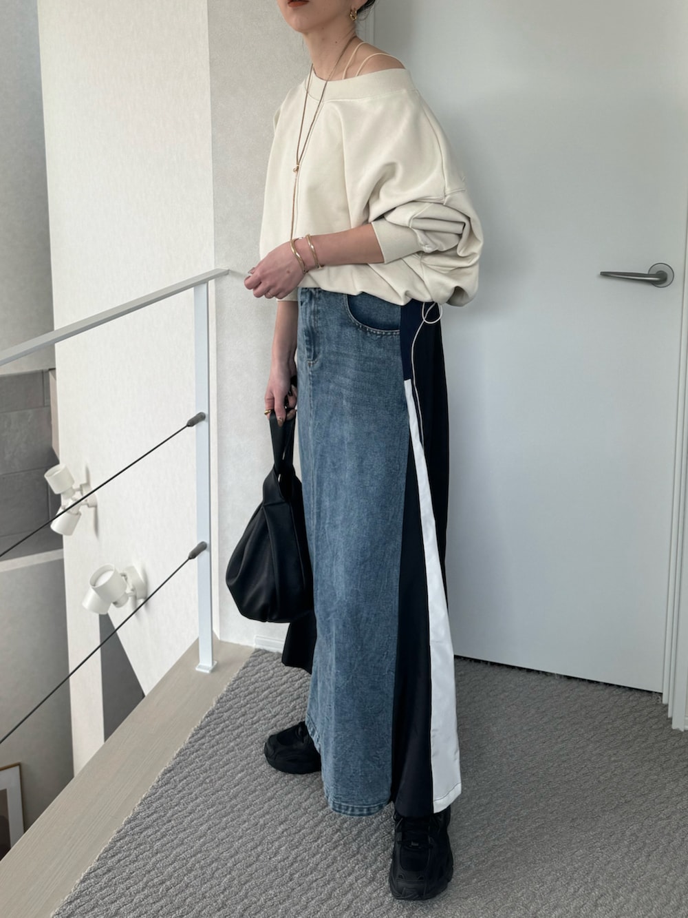 ホワイト系のスウェット、ブルー系のスカート、ブラック系のスニーカーを着用したレディースの春コーディネートの3枚目の写真