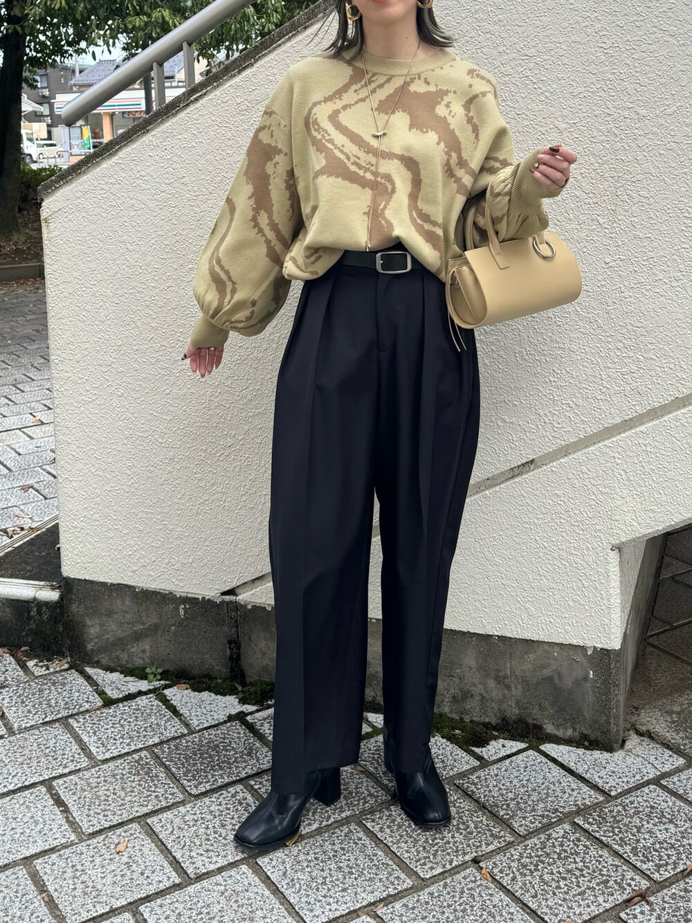 グリーン系のニット/セーター、ブラック系のその他パンツ、ベージュ系のハンドバッグを着用したレディースの秋コーディネートの3枚目の写真