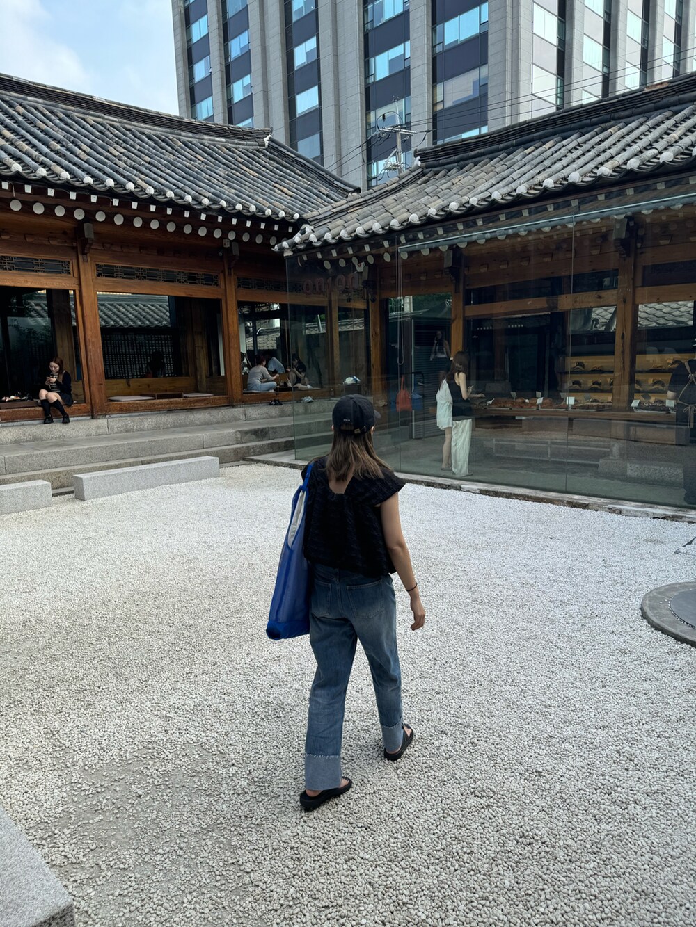 ブラック系のその他トップス、ブルー系のデニムパンツ、ブルー系のトートバッグを着用したレディースの夏コーディネートの4枚目の写真