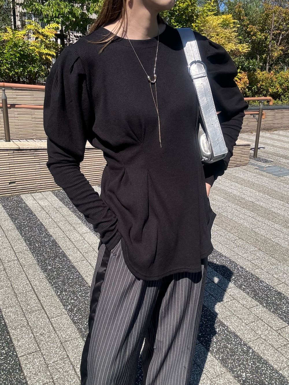 ブラック系のTシャツ/カットソー、シルバー系のショルダーバッグ、グレー系のスラックスを着用したレディースの秋コーディネートの4枚目の写真