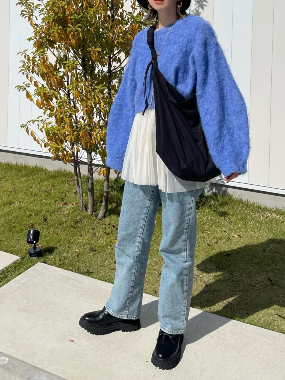 ブルー系のニット/セーター、ホワイト系のキャミソール、ブラック系のショルダーバッグを着用したレディースの秋コーディネートの2枚目の写真