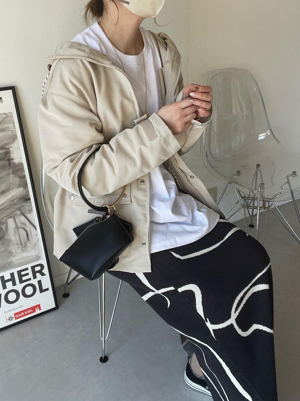 ホワイト系のマウンテンパーカー、グレー系のスカート、ブラック系のハンドバッグを着用したレディースの春コーディネートの2枚目の写真