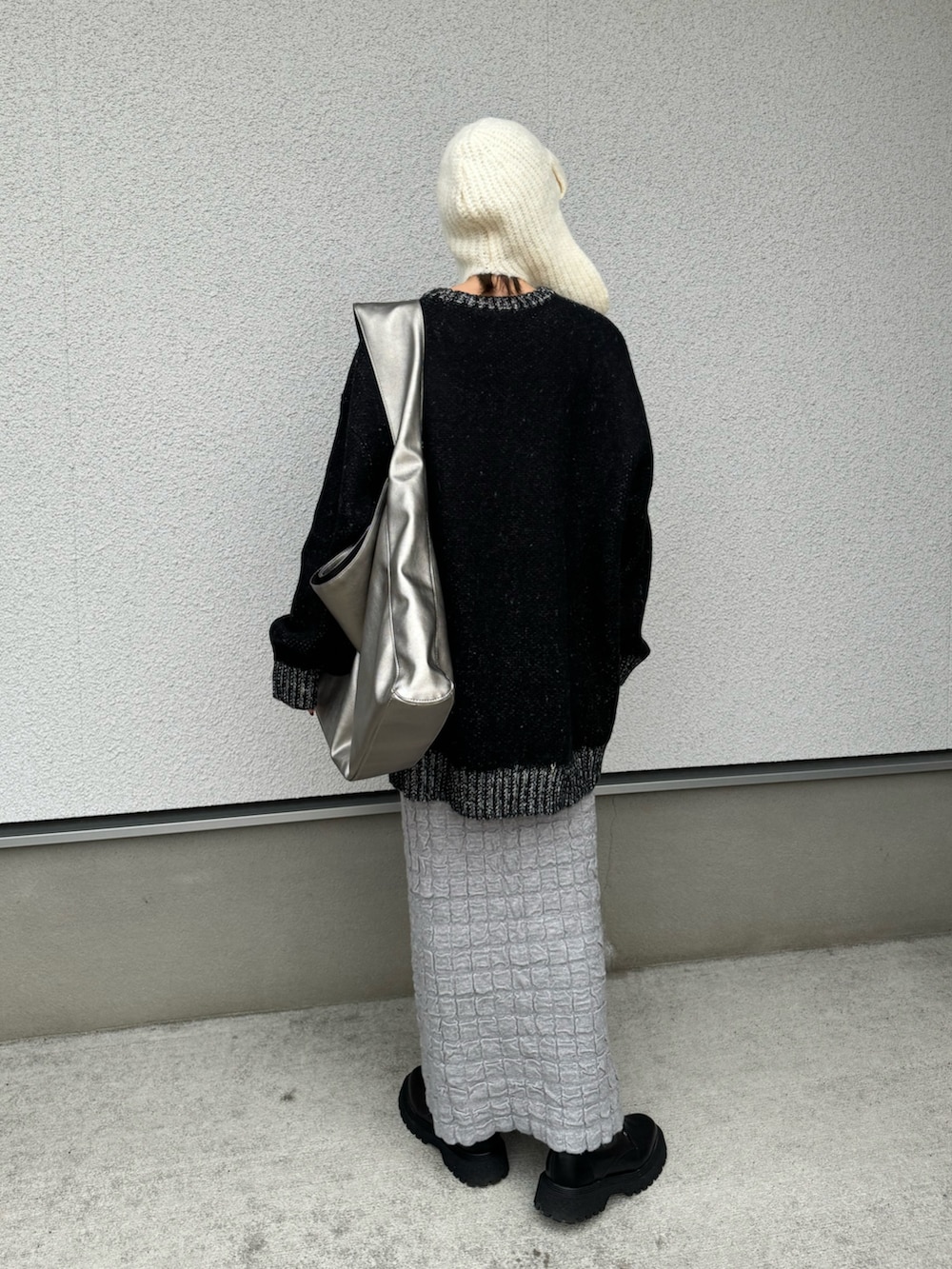ブラック系のニット/セーター、シルバー系のトートバッグ、ブラック系のブーツを着用したレディースの冬コーディネートの5枚目の写真
