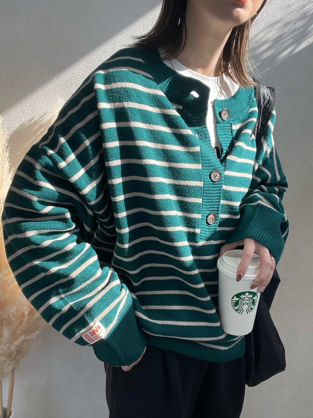 グリーン系のニット/セーター、ブラック系のショルダーバッグ、ホワイト系のスニーカーを着用したレディースの冬コーディネートの3枚目の写真