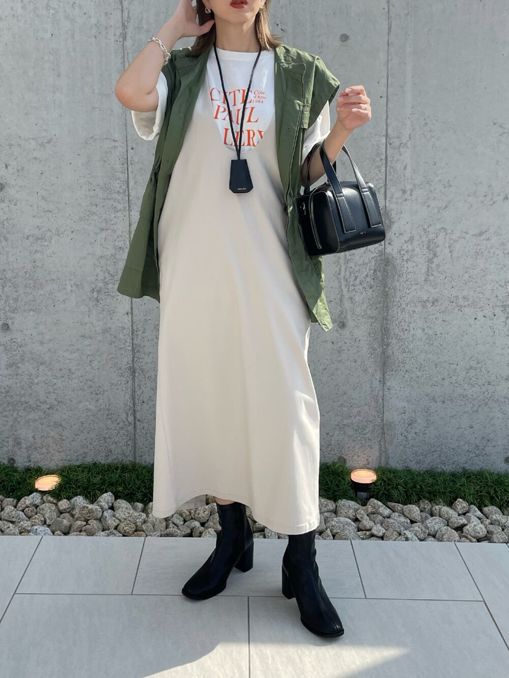 ブラック系のブーツ、ベージュ系のジャンパースカート、ブラック系のボストンバッグを着用したレディースの秋コーディネートの3枚目の写真