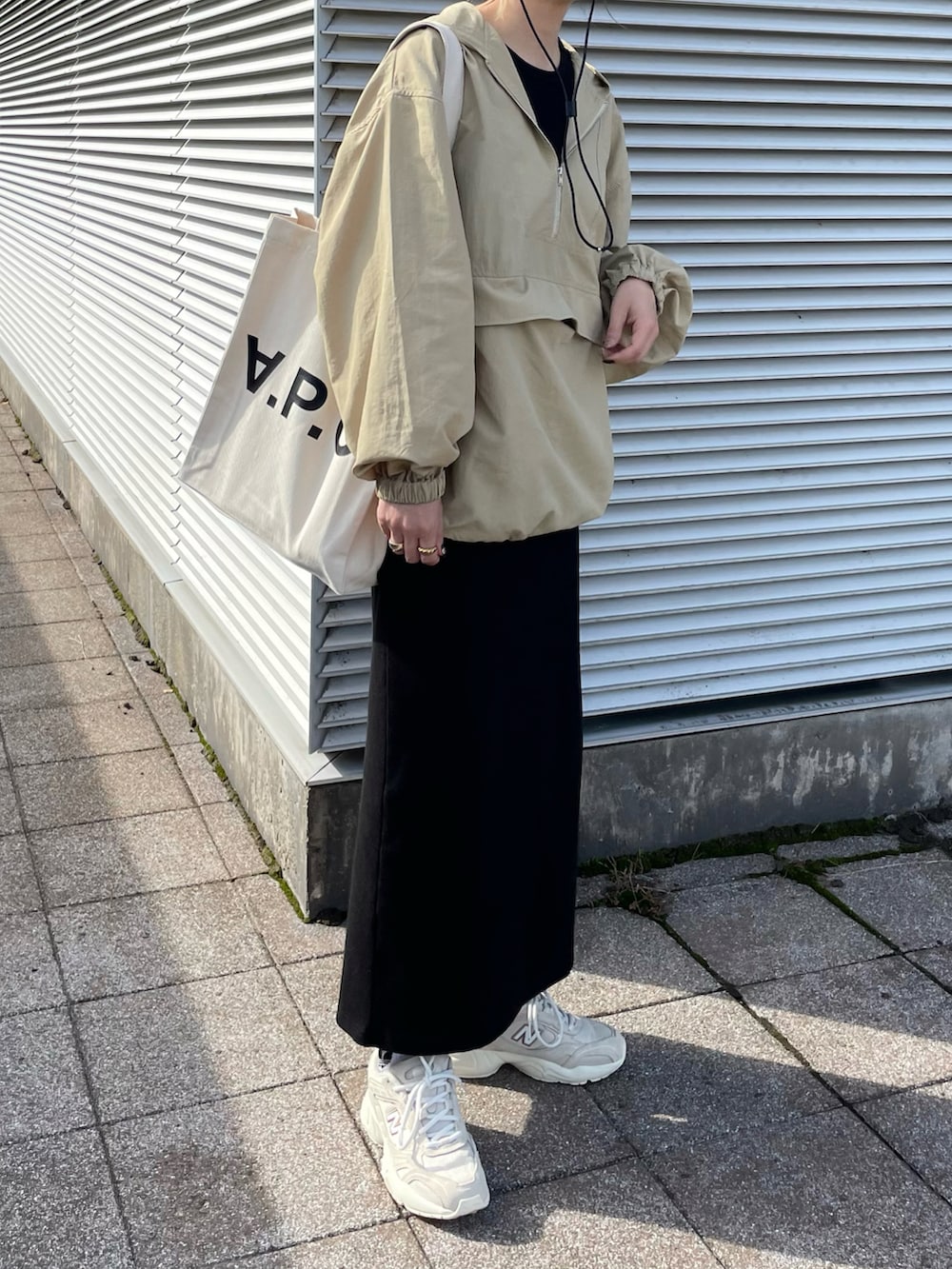 ベージュ系のナイロンジャケット、ブラック系のワンピース、ホワイト系のトートバッグを着用したレディースの秋コーディネートの3枚目の写真