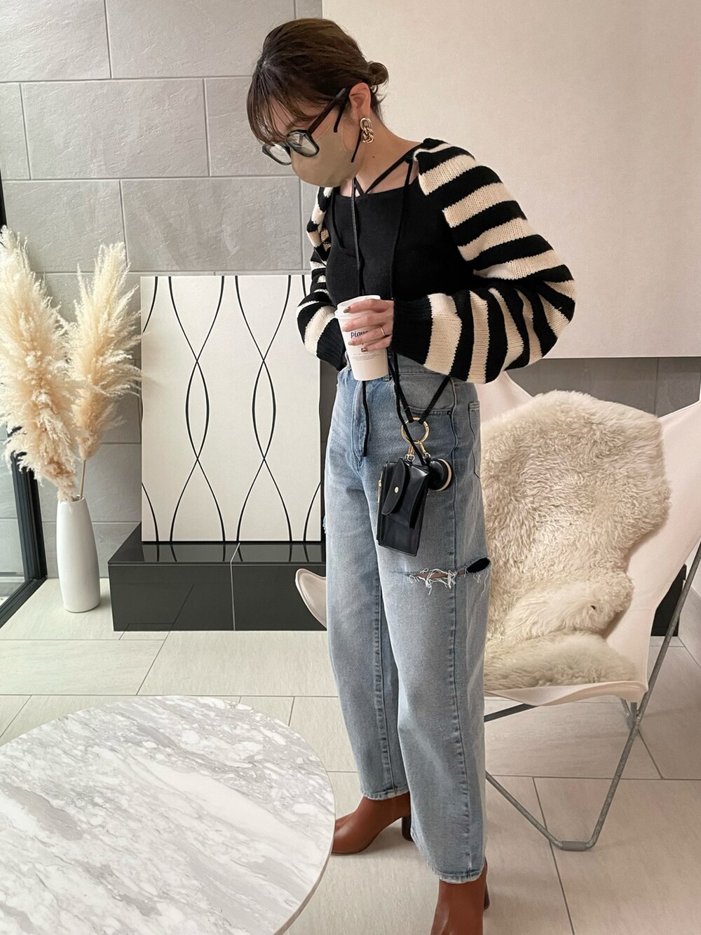 ブラック系のニット/セーター、ブラウン系のブーツ、ブラック系のショルダーバッグを着用したレディースの冬コーディネートの3枚目の写真