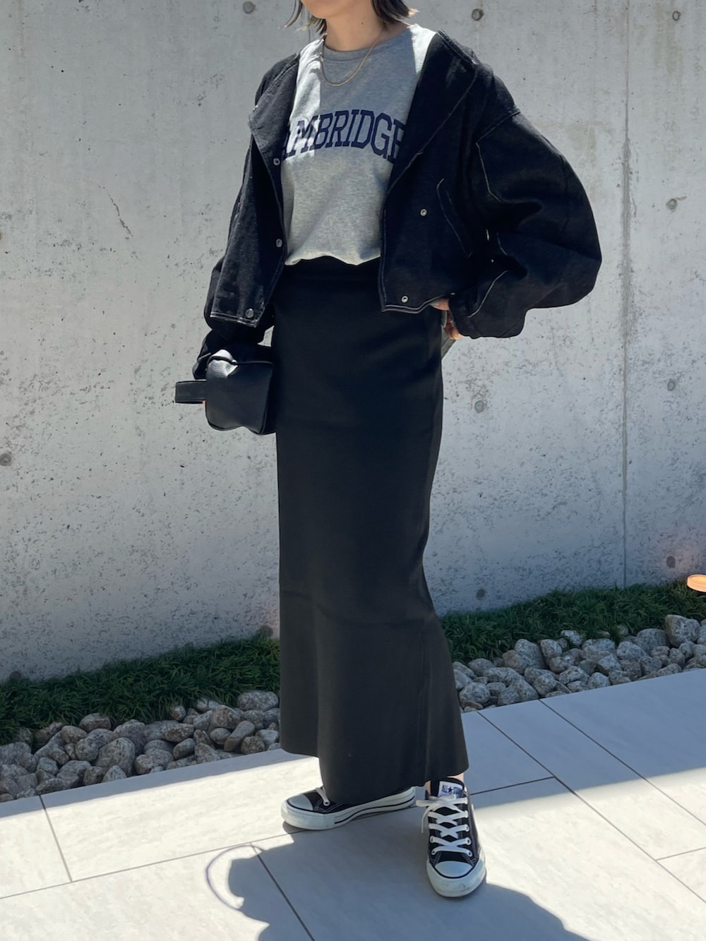 グレー系のTシャツ/カットソー、ブラック系のスカート、ブラック系のデニムジャケットを着用したレディースの秋コーディネートの3枚目の写真