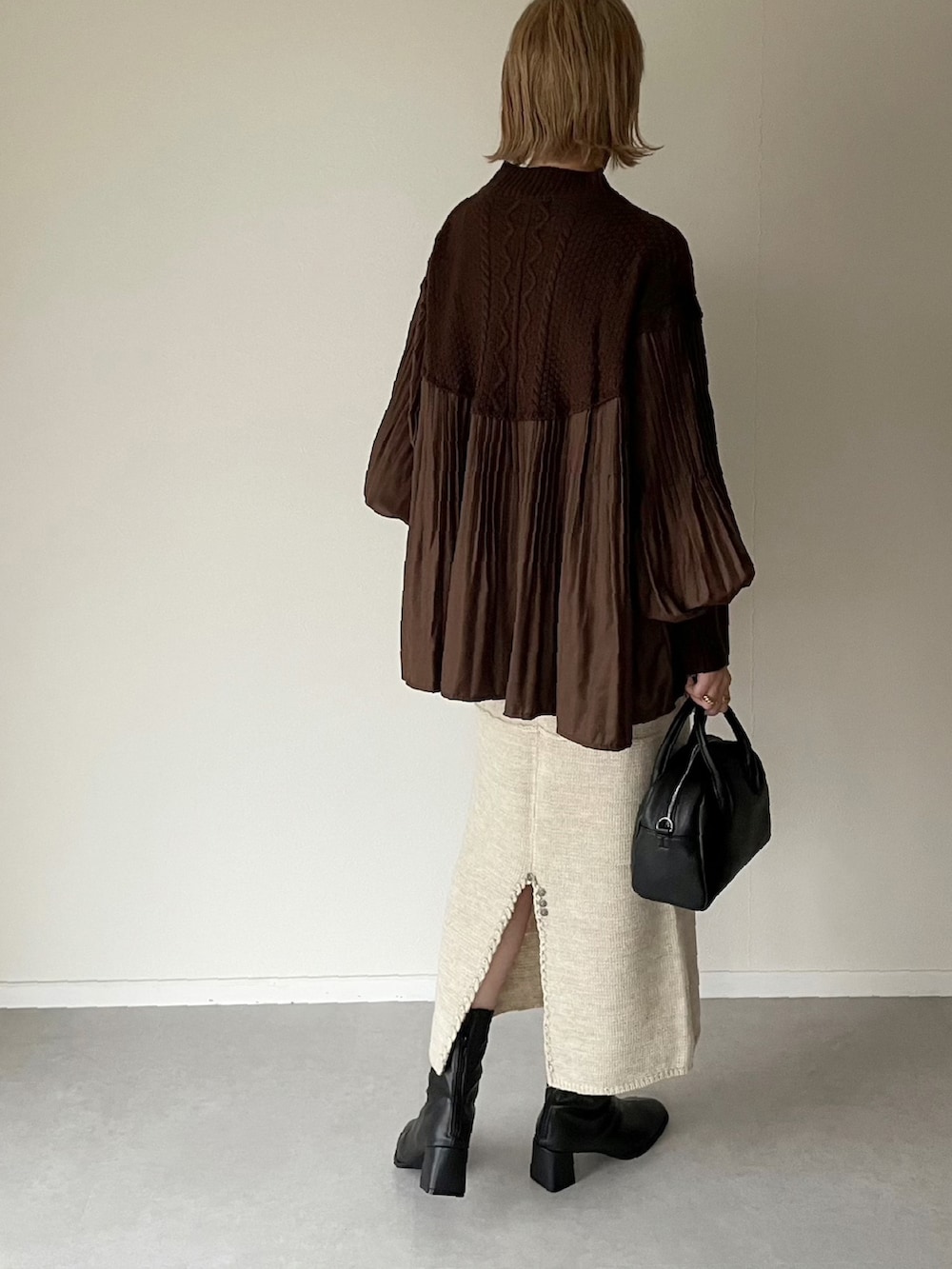 ブラウン系のニット/セーター、ベージュ系のスカート、ブラック系のボストンバッグを着用したレディースの秋コーディネートの2枚目の写真