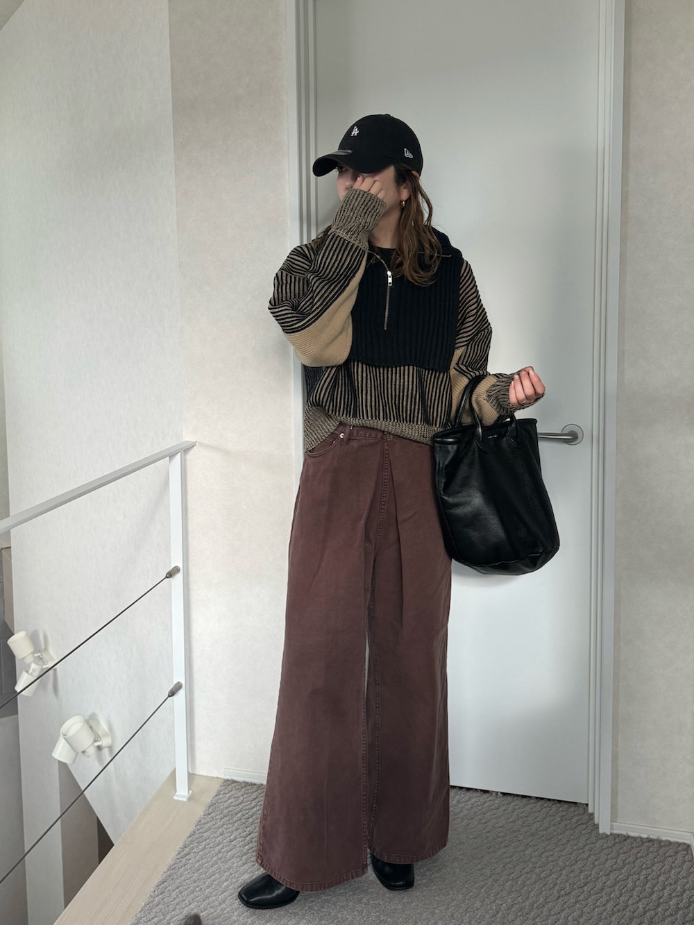 ブラック系のニット/セーター、ブラウン系のデニムパンツ、ブラック系のトートバッグを着用したレディースの冬コーディネートの2枚目の写真