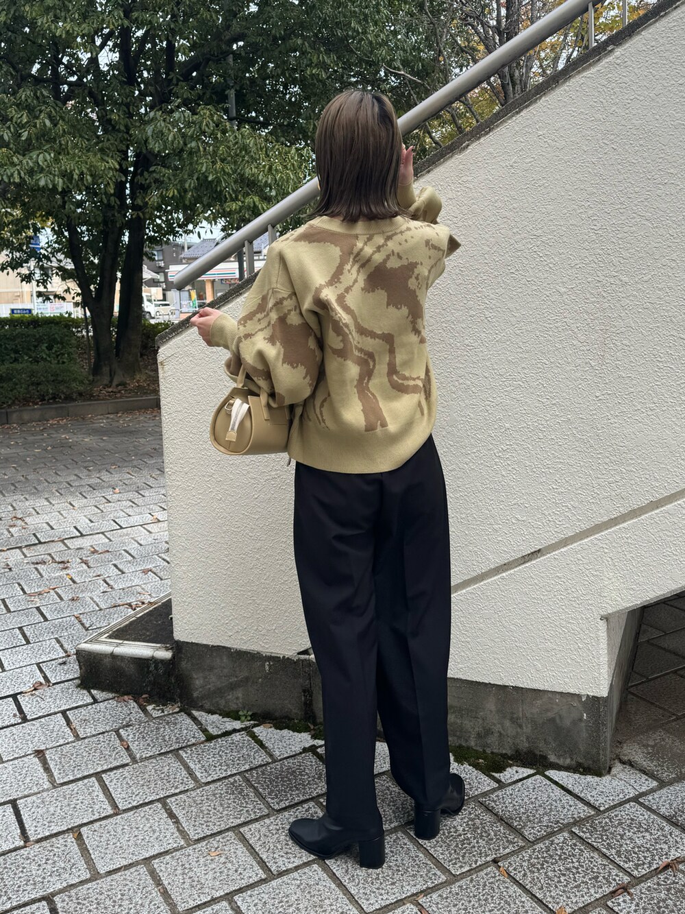 グリーン系のニット/セーター、ブラック系のその他パンツ、ベージュ系のハンドバッグを着用したレディースの秋コーディネートの4枚目の写真