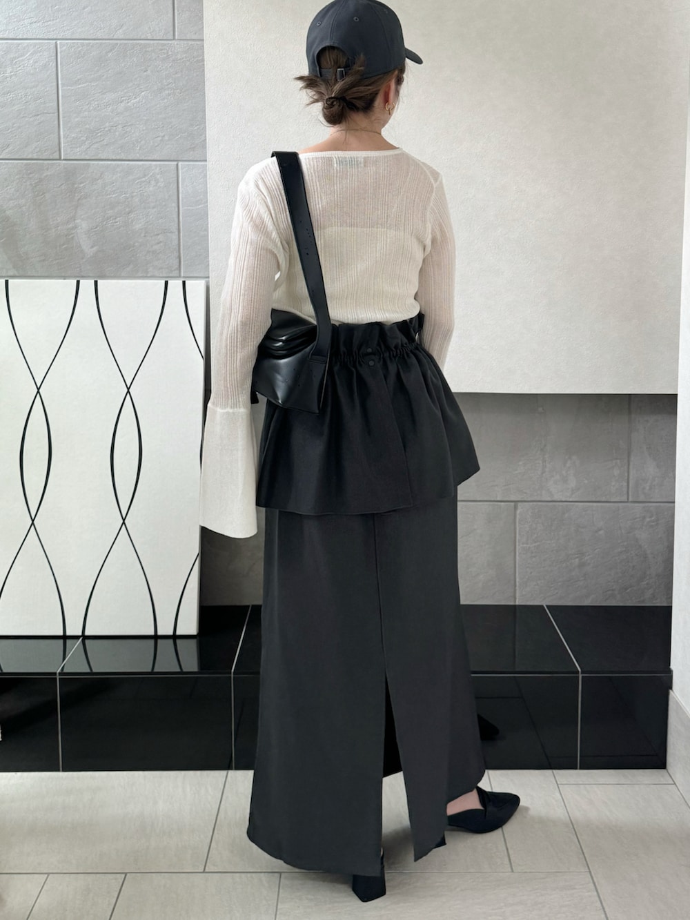 グレー系のスカート、ホワイト系のニット/セーター、ブラック系のローファーを着用したレディースの秋コーディネートの4枚目の写真