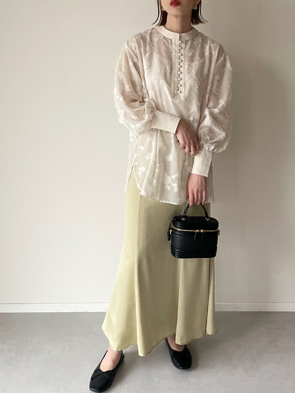 ホワイト系のシャツ/ブラウス、イエロー系のスカート、ブラック系のパンプスを着用したレディースの春コーディネートの2枚目の写真