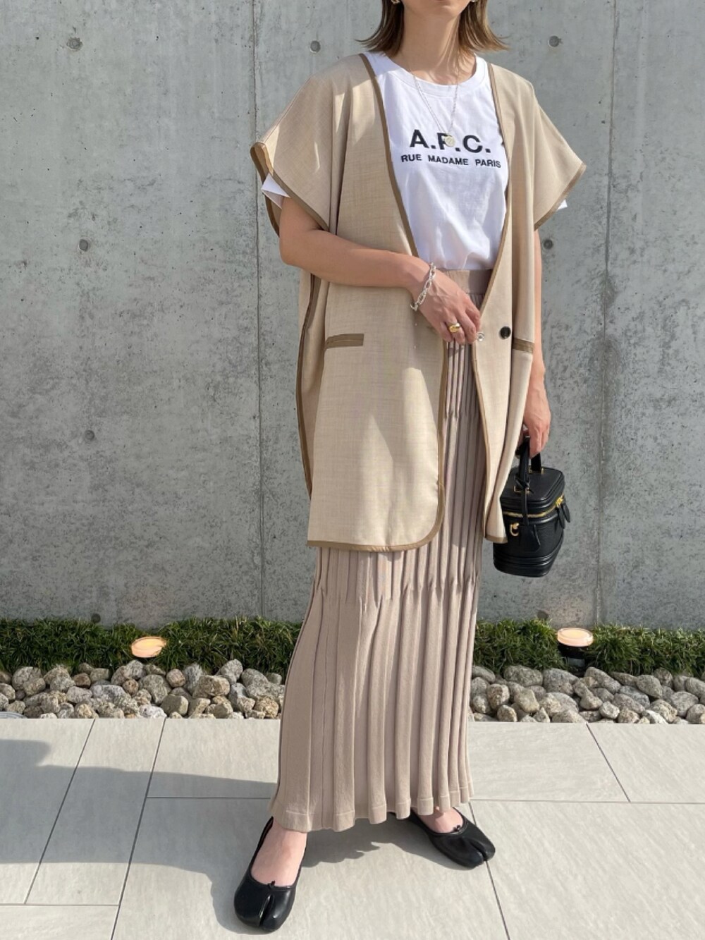 ベージュ系のスカート、ベージュ系のベスト、ホワイト系のTシャツ/カットソーを着用したレディースの夏コーディネートの2枚目の写真