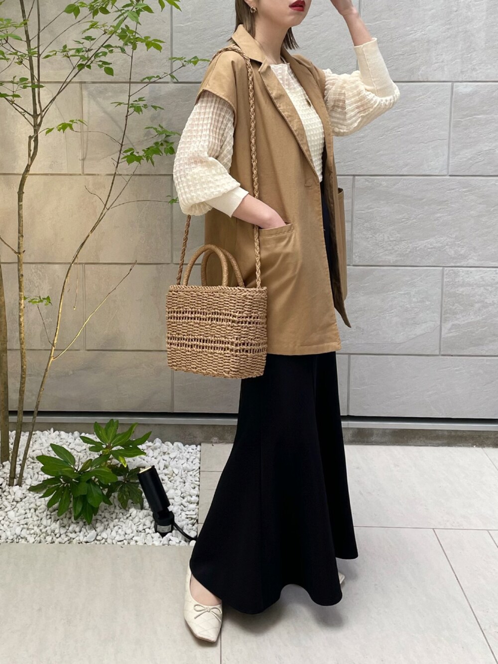 イエロー系のベスト、ホワイト系のニット/セーター、ホワイト系のパンプスを着用したレディースの春コーディネートの2枚目の写真