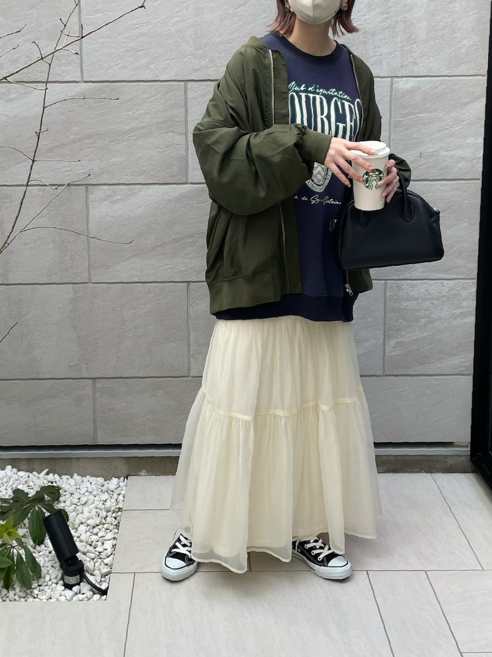 グリーン系のブルゾン、ホワイト系のスカート、ブルー系のスウェットを着用したレディースの春コーディネートの4枚目の写真
