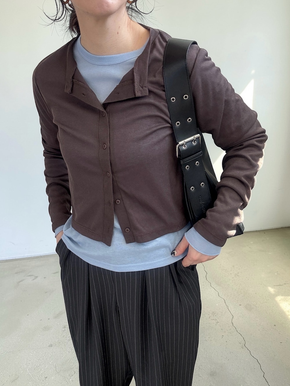 ブラウン系のカーディガン/ボレロ、グレー系のスラックス、ブラック系のハンドバッグを着用したレディースの春コーディネートの4枚目の写真