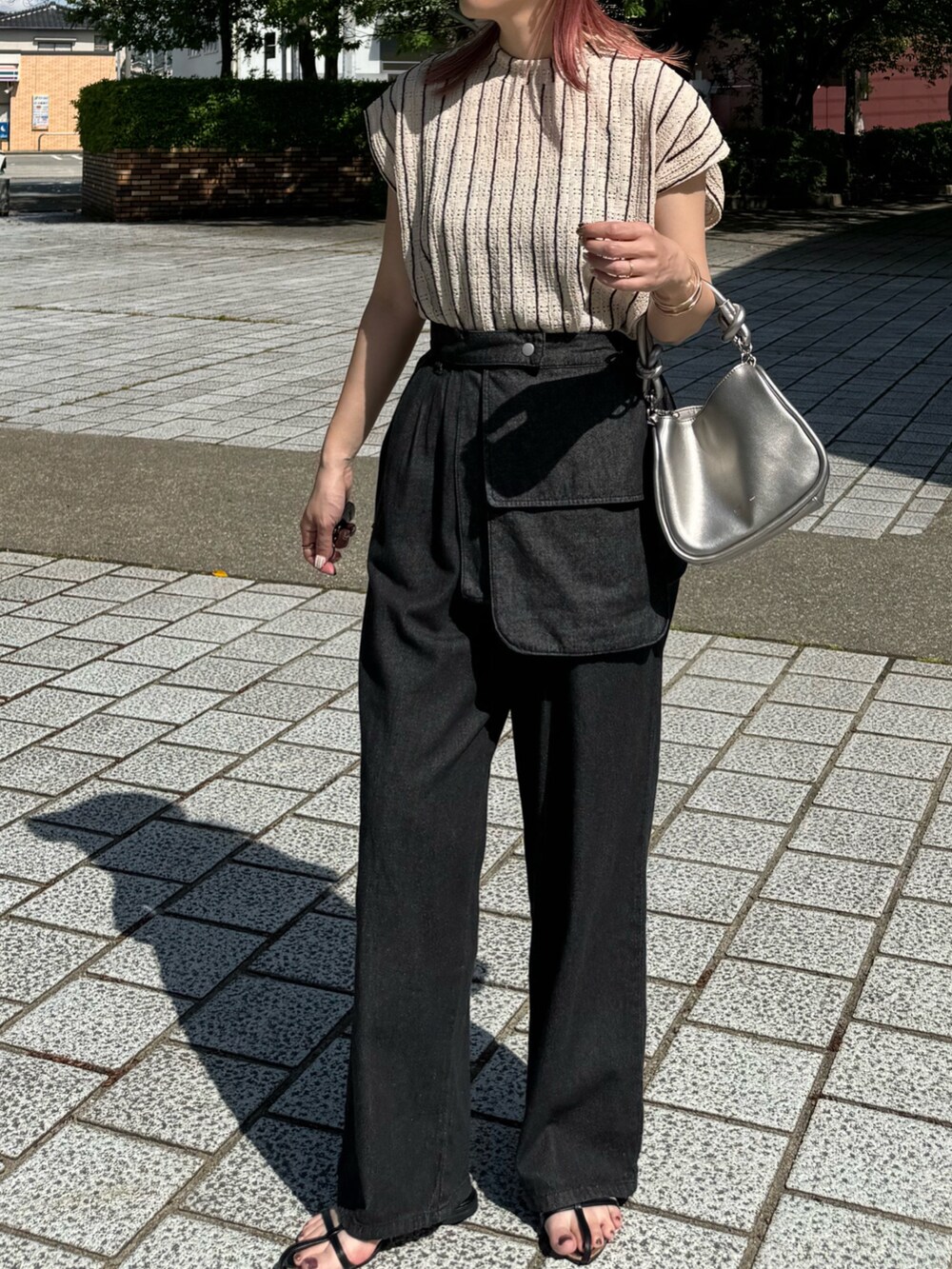 ブラック系のデニムパンツ、ブラック系のサンダル、シルバー系のショルダーバッグを着用したレディースの春コーディネートの4枚目の写真