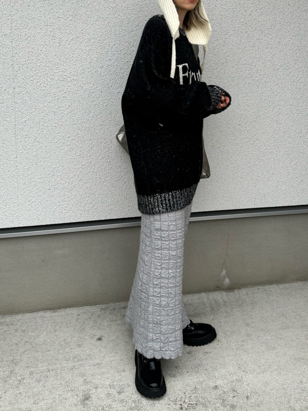 ブラック系のニット/セーター、シルバー系のトートバッグ、ブラック系のブーツを着用したレディースの冬コーディネートの3枚目の写真