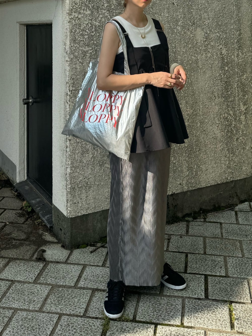 グレー系のスカート、ブラック系のその他トップス、シルバー系のトートバッグを着用したレディースの夏コーディネートの2枚目の写真