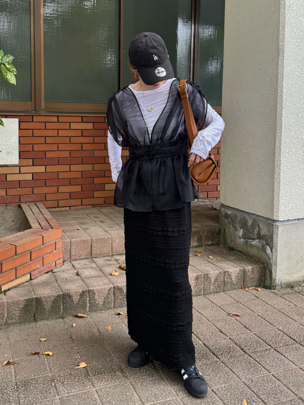 ホワイト系のTシャツ/カットソー、ブラック系のスカート、ブラック系のスニーカーを着用したレディースの秋コーディネートの3枚目の写真