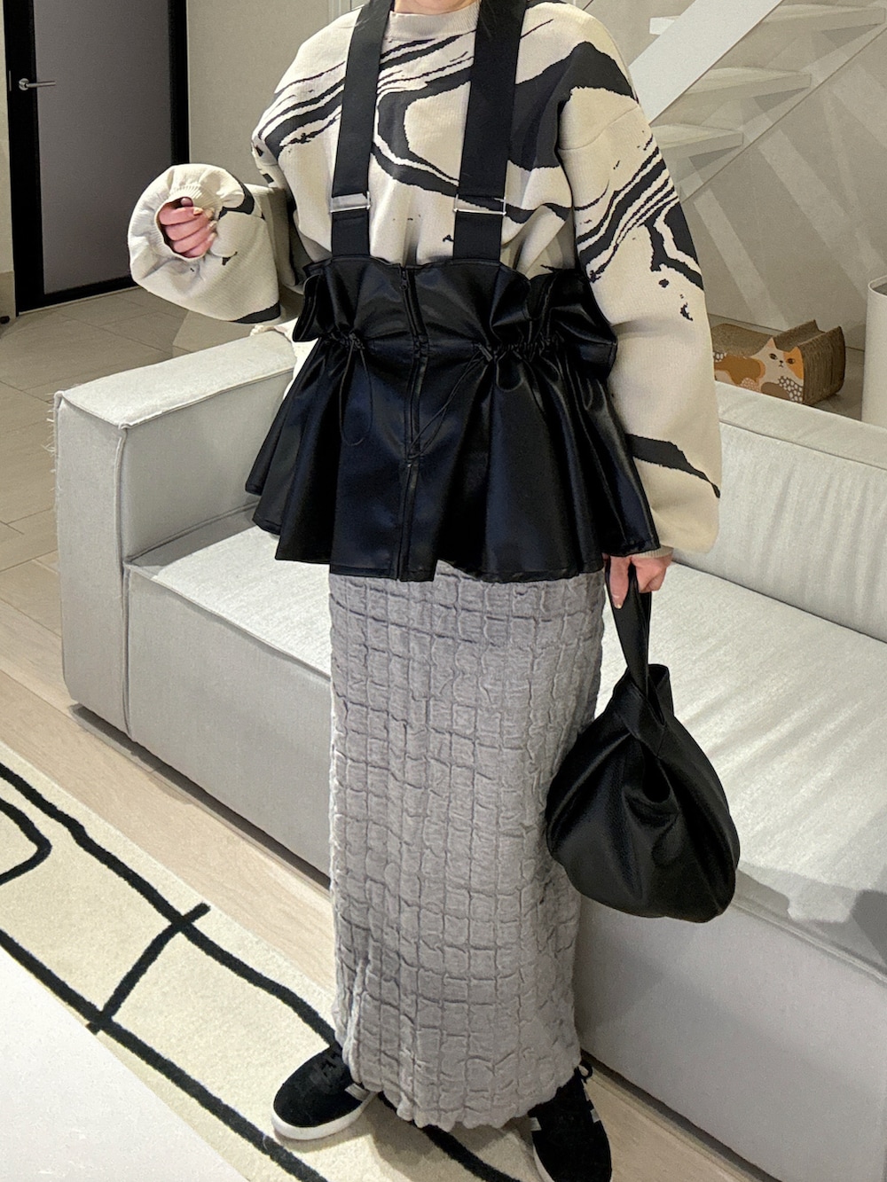 グレー系のスカート、ブラック系のベスト、ホワイト系のニット/セーターを着用したレディースの冬コーディネートの4枚目の写真