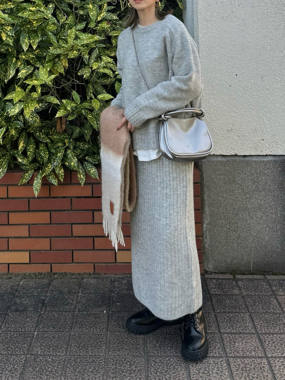 グレー系のワンピース、ブラック系のライダースジャケット、シルバー系のショルダーバッグを着用したレディースの冬コーディネートの3枚目の写真