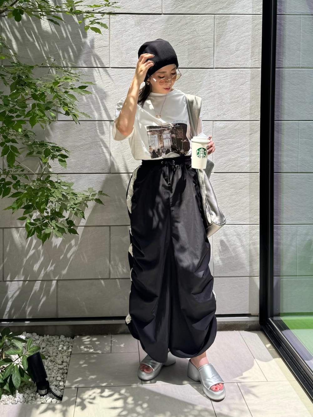 ブラック系のスカート、ホワイト系のTシャツ/カットソー、シルバー系のサンダルを着用したレディースの夏コーディネートの2枚目の写真