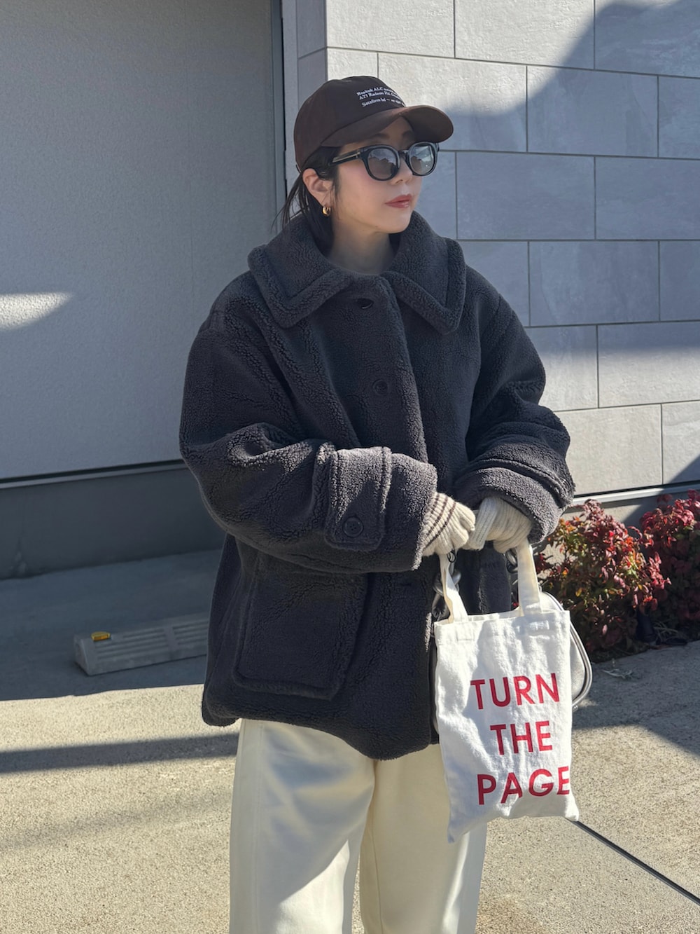 グレー系のステンカラーコート、ホワイト系のスウェットパンツ、ブラウン系のキャップを着用したレディースの冬コーディネートの4枚目の写真