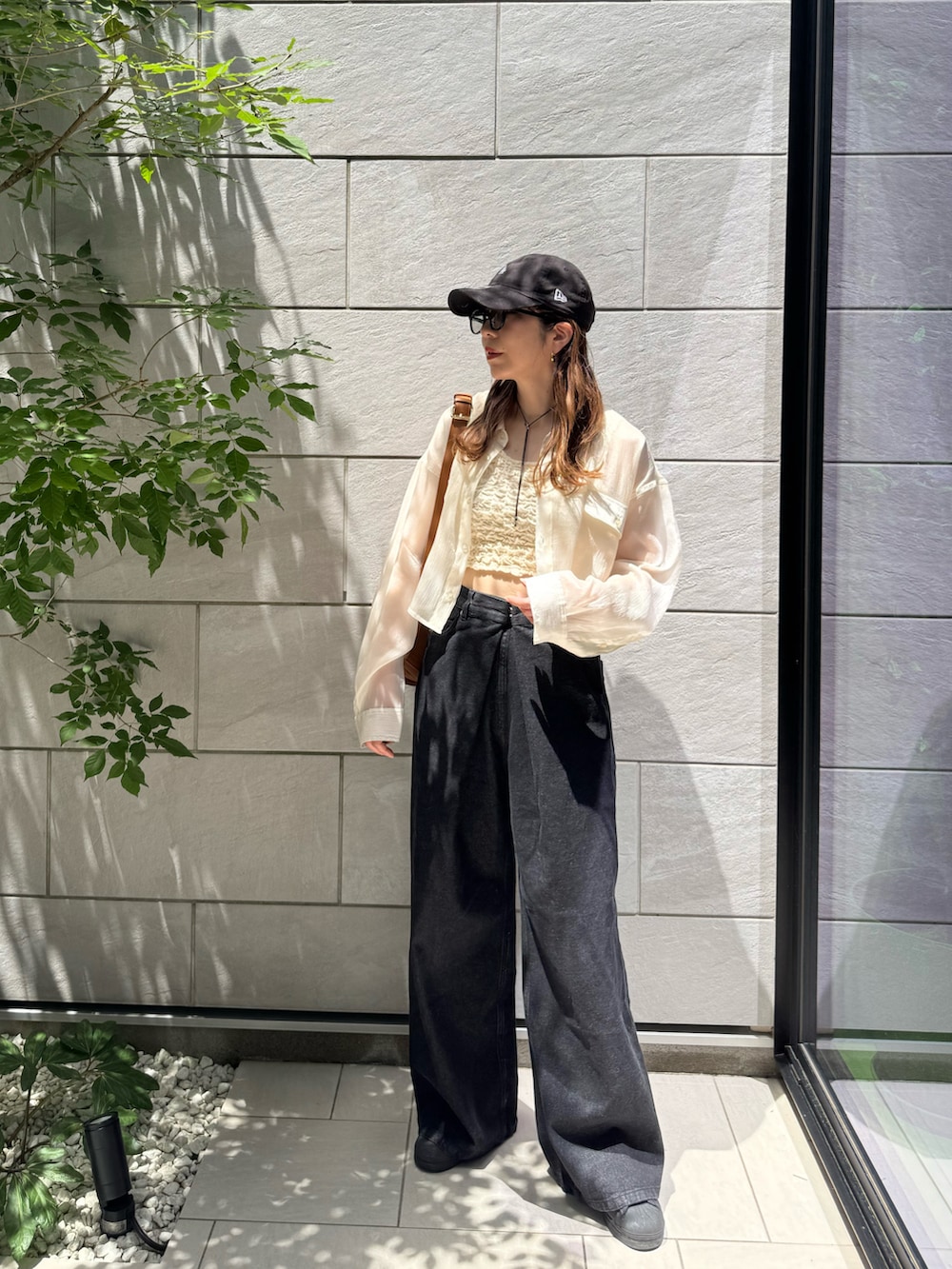 ホワイト系のタンクトップ、ブラック系のデニムパンツ、ブラック系のスニーカーを着用したレディースの夏コーディネートの2枚目の写真