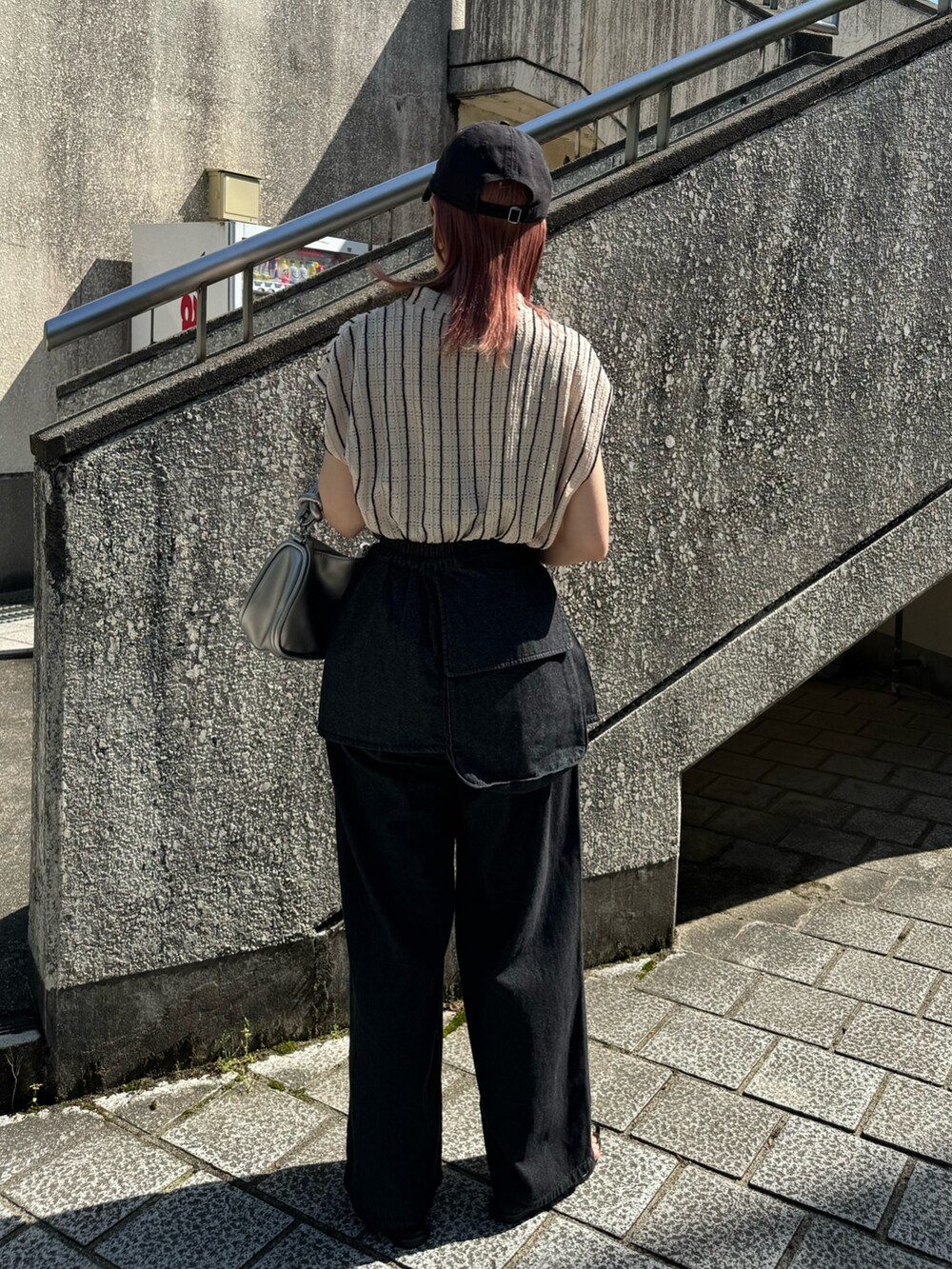 ブラック系のデニムパンツ、ブラック系のサンダル、シルバー系のショルダーバッグを着用したレディースの春コーディネートの5枚目の写真