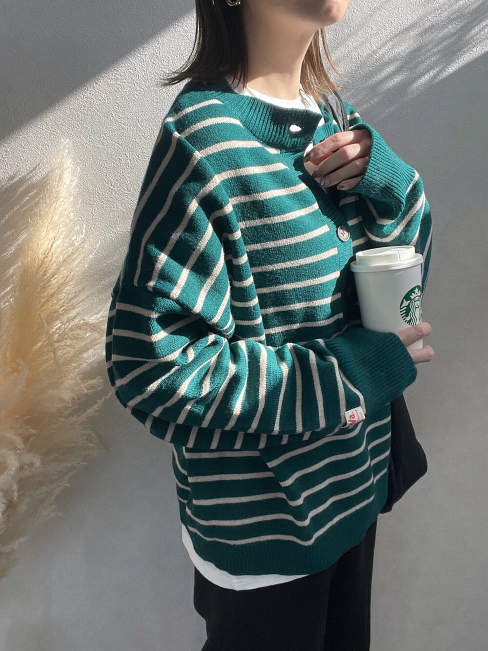 グリーン系のニット/セーター、ブラック系のショルダーバッグ、ホワイト系のスニーカーを着用したレディースの冬コーディネートの4枚目の写真