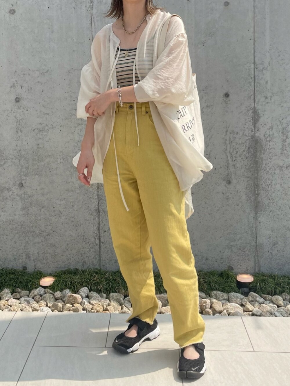 イエロー系のデニムパンツ、ベージュ系のキャミソール、ホワイト系のシャツ/ブラウスを着用したレディースの夏コーディネートの2枚目の写真