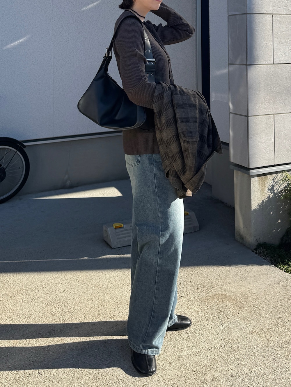 ブルー系のデニムパンツ、ブラウン系のカーディガン/ボレロ、ブラック系のハンドバッグを着用したレディースの冬コーディネートの5枚目の写真