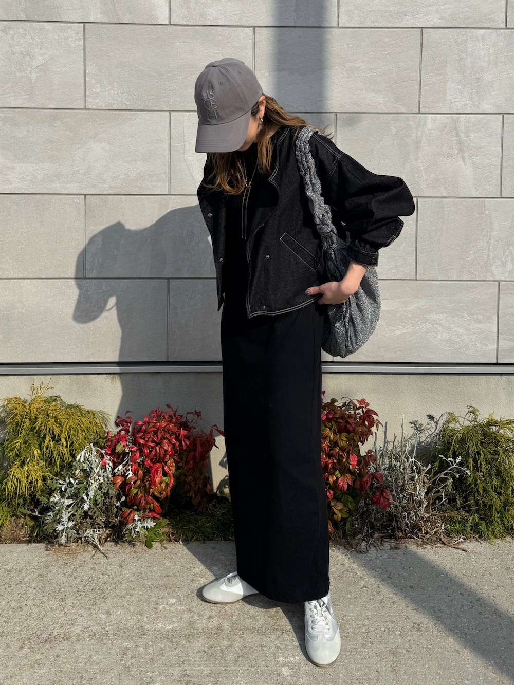 グレー系のスニーカー、ブラック系のワンピース、ブラック系のデニムジャケットを着用したレディースの春コーディネートの3枚目の写真