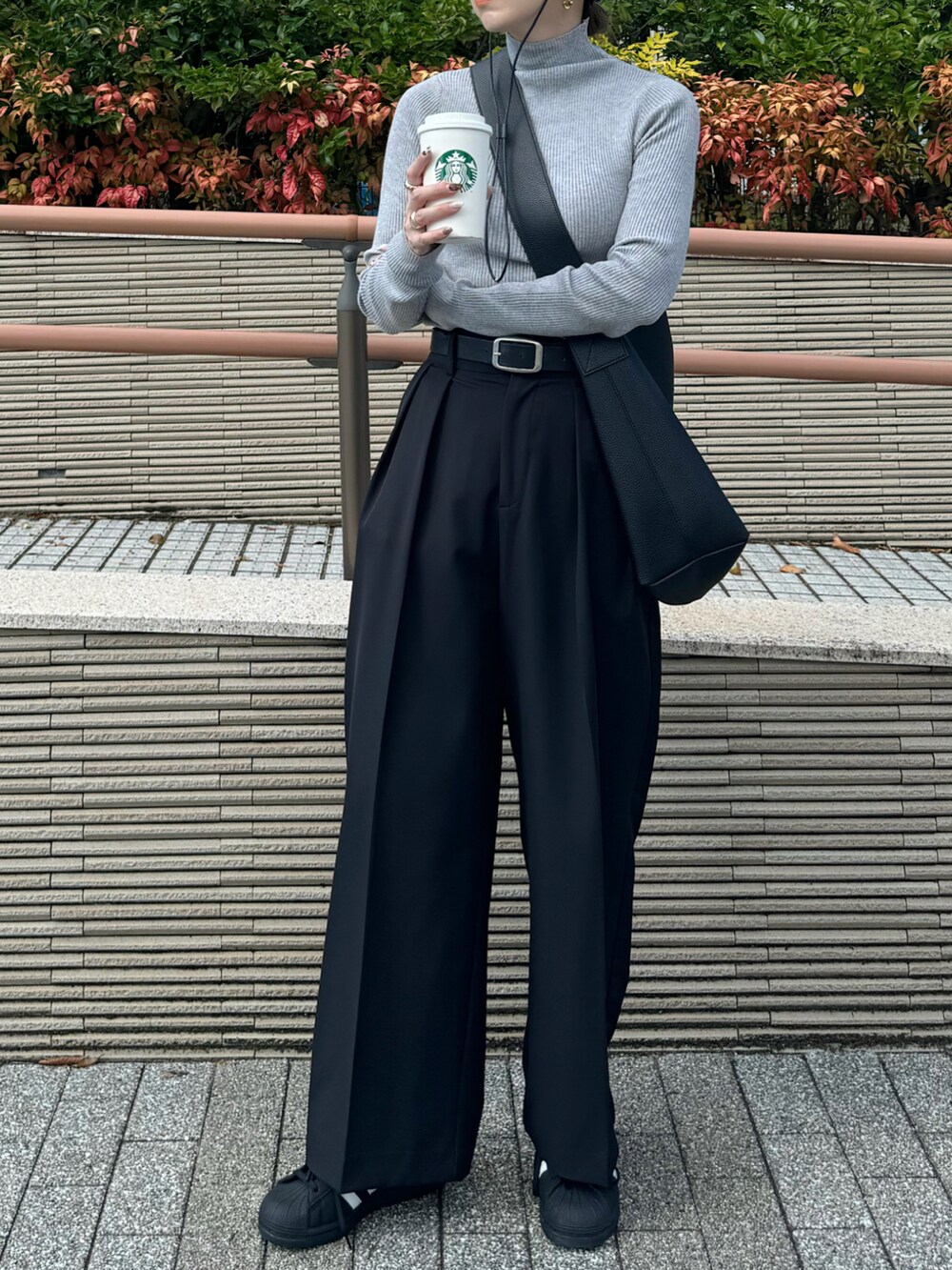 グレー系のニット/セーター、ブラック系のその他パンツ、ブラック系のスニーカーを着用したレディースの秋コーディネートの2枚目の写真