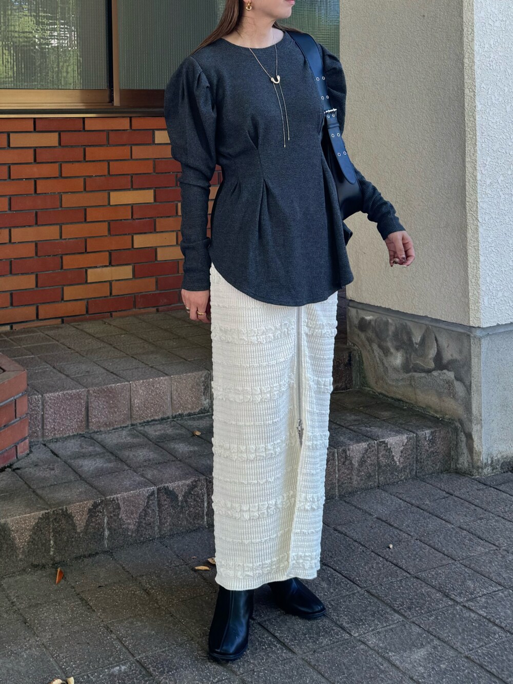 ホワイト系のスカート、グレー系のTシャツ/カットソー、ブラック系のハンドバッグを着用したレディースの秋コーディネートの5枚目の写真