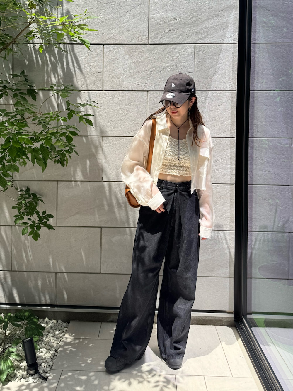 ホワイト系のタンクトップ、ブラック系のデニムパンツ、ブラック系のスニーカーを着用したレディースの夏コーディネートの3枚目の写真